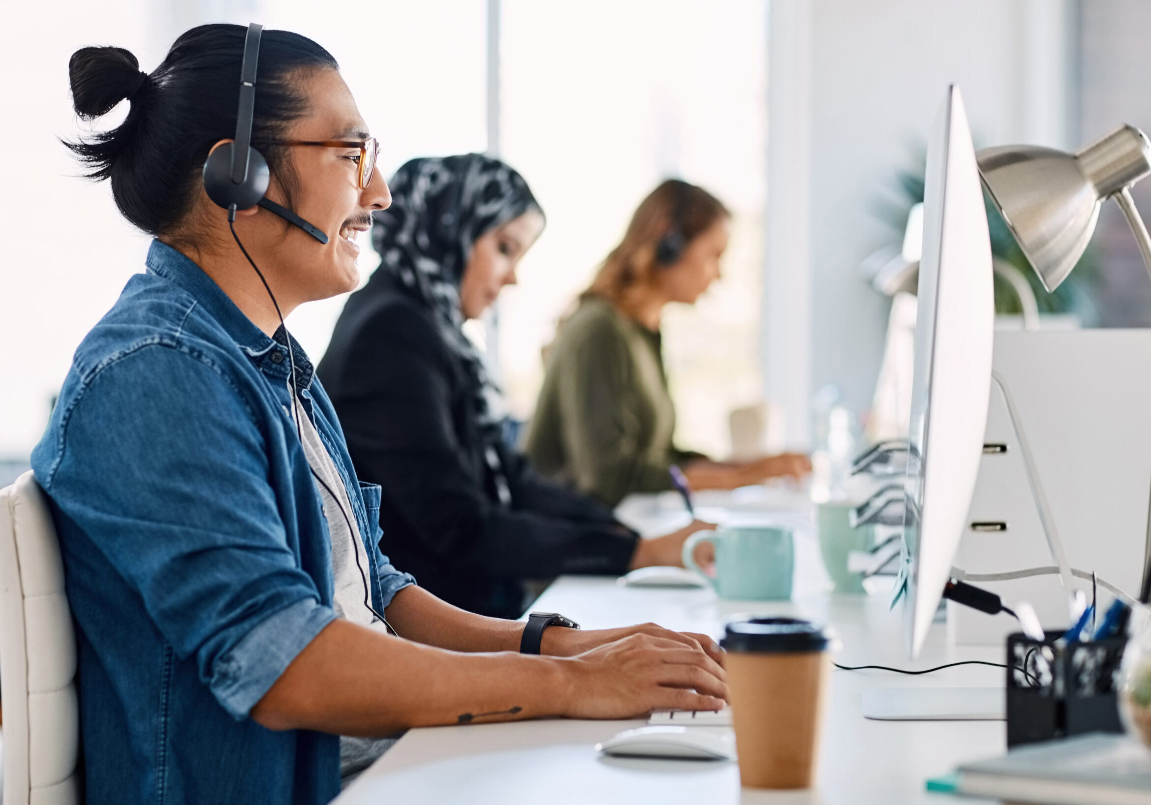 Shot of a group of young call centre agents wearing headsets and working on their computers in an office